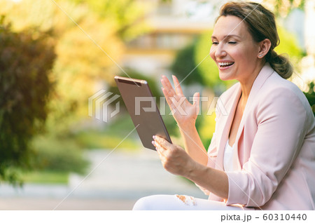 Smiling businesswoman with a tablet in the park. Smiling businesswoman with a tablet in the park. 60310440