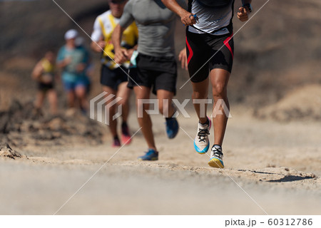 Runners running shoes on trail run. Ultra running athletes legs close up on running in rock path trail 60312786