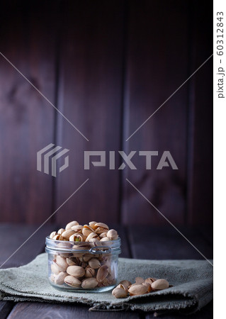 Pistachios in glass jars on a wooden background Pistachios in glass jars on a wooden background 60312843