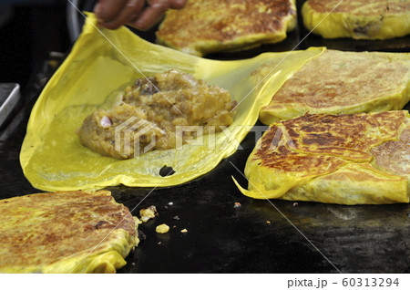 Malaysian street food called Murtabak. Cook by Hawkers. In it there is a mixture of meat, eggs and onions. Eaten with a special gravy. 60313294