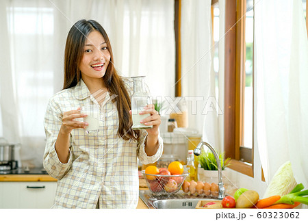 Asian beautiful girl hold glass and bottle of milk in the kitchen Asian beautiful girl hold glass and bottle of milk in the kitchen 60323062