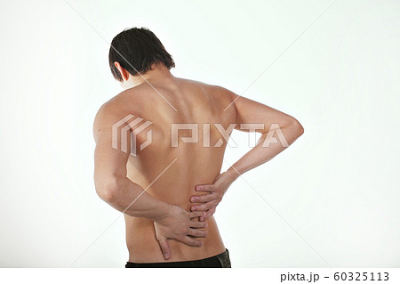 back pain: a man on a white background holding his sore torso 60325113