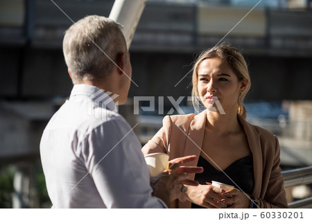 Old boss and business woman talk and drink coffee 60330201