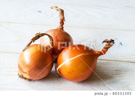 Three raw fresh yellow onions on a wooden rustic table. Vegetables, vegetarian and healthy eating. 60331505