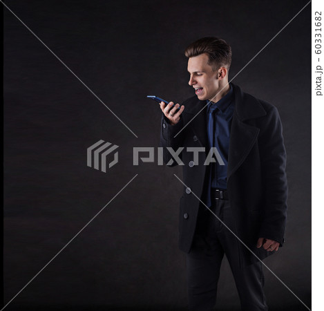 A handsome man in a coat screams while talking on the phone. A handsome man in a coat screams while talking on the phone. 60331682