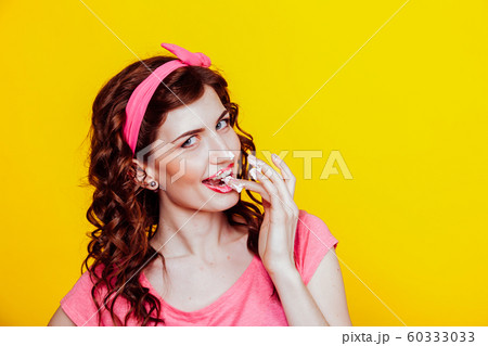 girl in pink dress pinup-style eats cream licks fingers 60333033