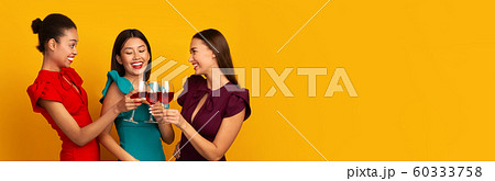Three Women Clinking Red Wine Glasses Laughing Standing, Yellow Background Three Women Clinking Red Wine Glasses Laughing Standing, Yellow Background 60333758