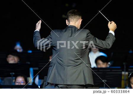 Male band conductor conducting his concert band Male band conductor conducting his concert band 60333864