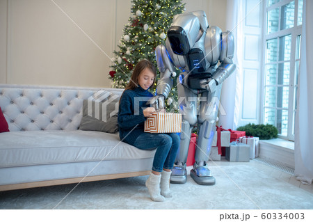 Girl in blue outfit sitting on the sofa next to christmas tree Girl in blue outfit sitting on the sofa next to christmas tree 60334003