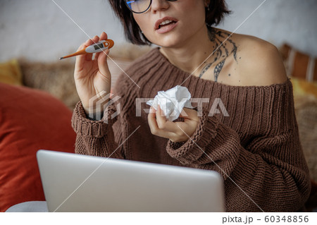 Upset young woman is demonstrating thermometer at home 60348856