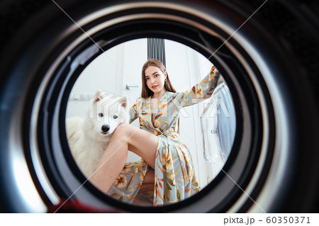 Young woman at home puts the dress in the drying machine. Young woman at home puts the dress in the drying machine. 60350371