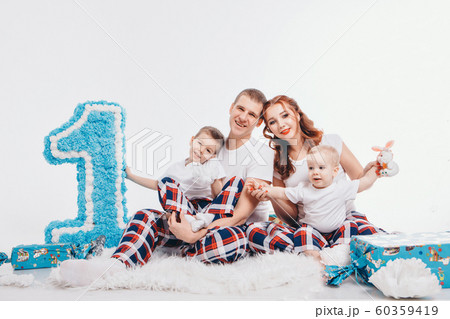 Birthday celebration: family sitting on the floor among the decoration: numbers 1, artificial flowers and gifts. The concept of birthday, holidays. copy space 60359419