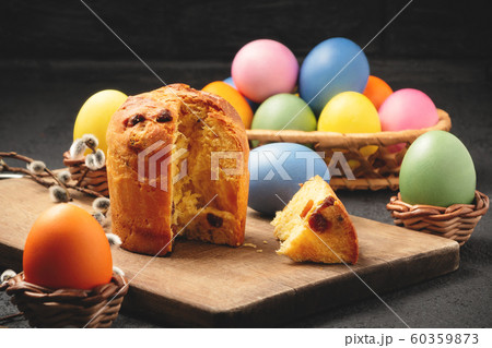 Easter cake on a cutting board and colored eggs on a table and in a wicker basket - traditional Easter breakfast 60359873
