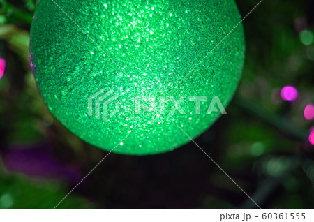 Shiny Christmas ball, on a blurred background of a green Christmas tree, part of the ball in the frame, open frame, close-up 60361555