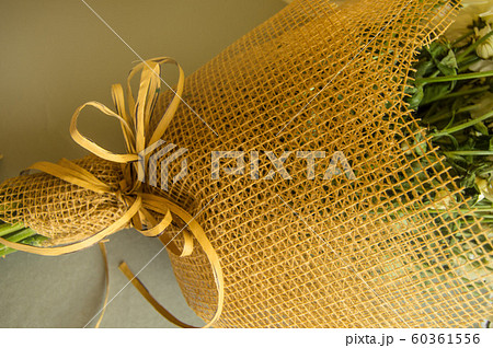 Example of packing a bouquet of flowers in a brown floral grid, close-up on a gray background Example of packing a bouquet of flowers in a brown floral grid, close-up on a gray background 60361556