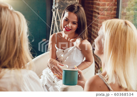 Girlfriends are sitting at a table in a cafe and talking. 60368534