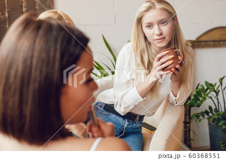 Girlfriends are sitting at a table in a cafe and talking. 60368551