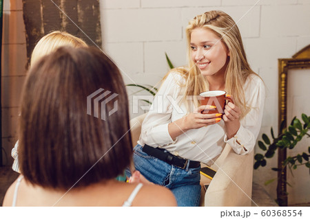 Girlfriends are sitting at a table in a cafe and talking. Girlfriends are sitting at a table in a cafe and talking. 60368554