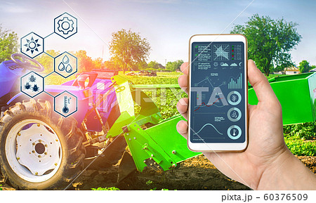 Farmer holds smartphone with infographic on tractor background with potato digger. Farming and smart agriculture. Agricultural machinery, data analyzing on plants status. Harvesting. Farmer holds smartphone with infographic on tractor background with potato digger. Farming and smart agriculture. Agricultural machinery, data analyzing on plants status. Harvesting. 60376509