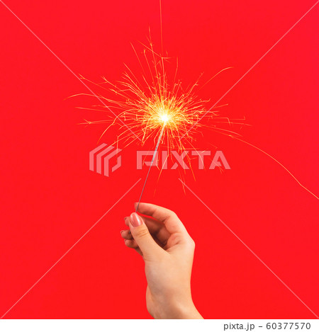 Bright burning Christmas sparkler in female hand Bright burning Christmas sparkler in female hand 60377570