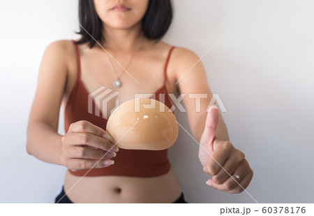 Woman hands holding silicone implants for breast and showing thumb up,Copy space for text on white background Woman hands holding silicone implants for breast and showing thumb up,Copy space for text on white background 60378176