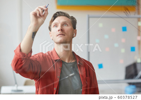 Tattooed Man Writing on Glass Wall in Office 60378527