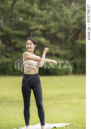 芝生の公園でストレッチをする女性　準備運動 60378617