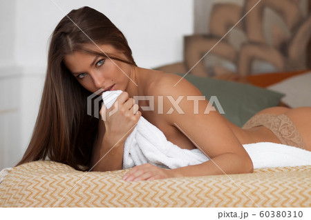 Provocative lady with towel lying on bed 60380310