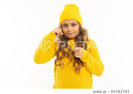 European attractive girl in a yellow hat twists at the temple on a white background 60382585
