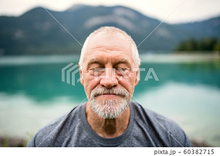 A front view portrait of senior man pensioner standing outdoors in nature. 60382715