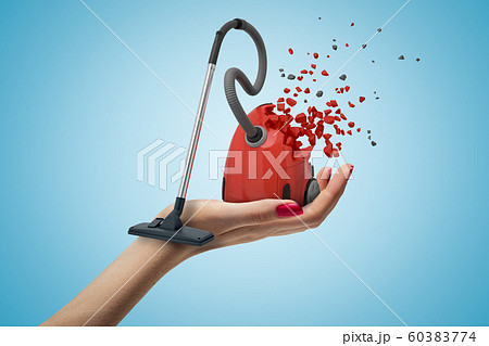 Female hand with red vacuum cleaner shattering into pieces on blue background Female hand with red vacuum cleaner shattering into pieces on blue background 60383774