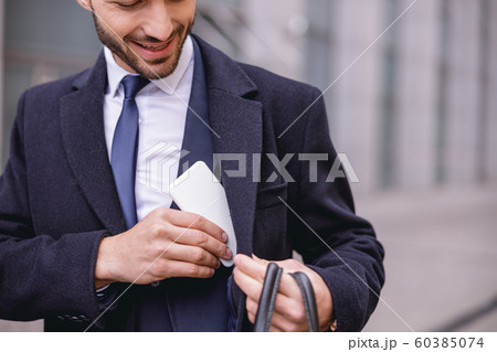Positive delighted bearded man hiding his gadget 60385074