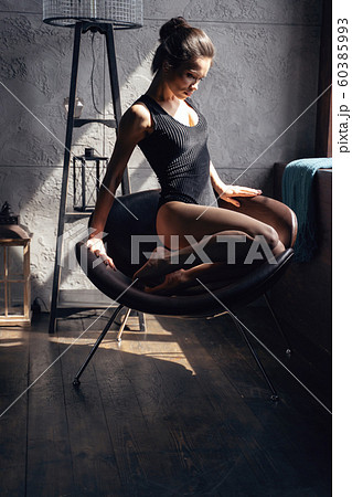 Girl sitting on brown chair and bending her knees 60385993