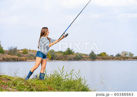 Beautiful young girl fishes on the lake. 60386663