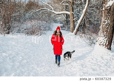 Young woman with her cute dog Husky on a walk in winter forest 60387329