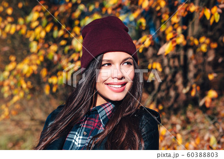 Stylish young woman in a hat and a plaid shirt in autumn park on a sunny day Stylish young woman in a hat and a plaid shirt in autumn park on a sunny day 60388803