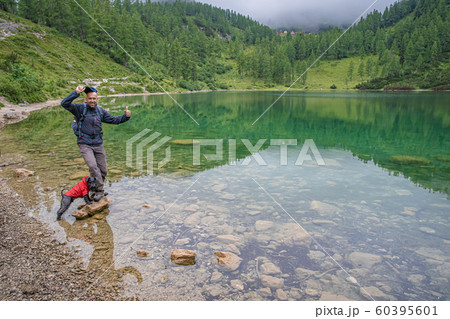 hikers in the austrian alps walk on mountain hiking trails in the woods around the lakes whith black dog hikers in the austrian alps walk on mountain hiking trails in the woods around the lakes whith black dog 60395601