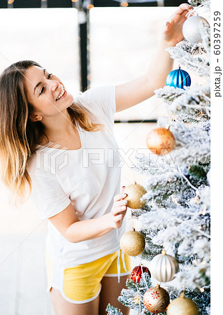 Woman decorating christmas tree in her living room Woman decorating christmas tree in her living room 60397259