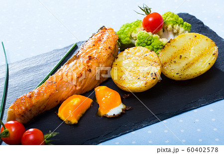 Tasty steak of fried salmon with potatoes and egg yolk on plate Tasty steak of fried salmon with potatoes and egg yolk on plate 60402578