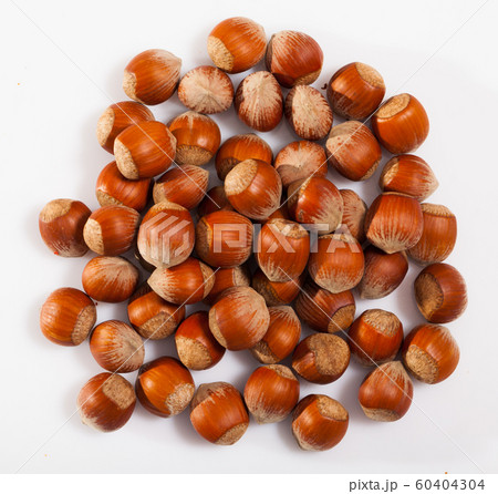 Unpeeled hazelnut on white surface closeup Unpeeled hazelnut on white surface closeup 60404304