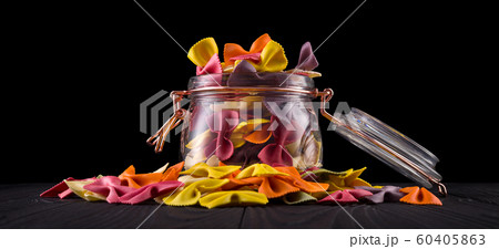 Jar of colorful farfalle pasta on wooden table isolated on black background Jar of colorful farfalle pasta on wooden table isolated on black background 60405863