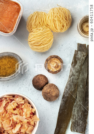 Ramen ingredients. Dried sea vegetable kelp, soba noodles, miso paste, tuna flakes, shiitake mushrooms, mirin sauce, sake in a cup, overhead shot, a flat lay composition Ramen ingredients. Dried sea vegetable kelp, soba noodles, miso paste, tuna flakes, shiitake mushrooms, mirin sauce, sake in a cup, overhead shot, a flat lay composition 60411758