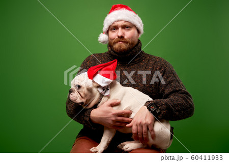 Man and dog in santa caps on empty green background Man and dog in santa caps on empty green background 60411933