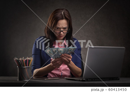 sad businesswoman at the table on a dark background with laptop and money. 60413450