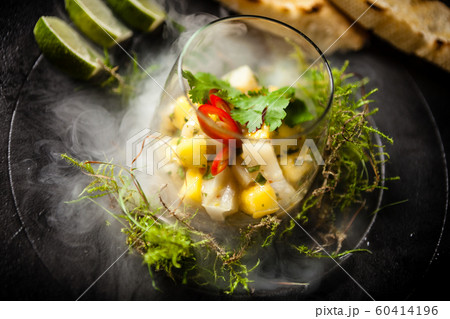 Scallop ceviche served in black bowl with liquid ice smoke 60414196