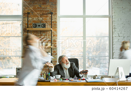 Tired boss resting at his workplace while people moving near blurred 60414267