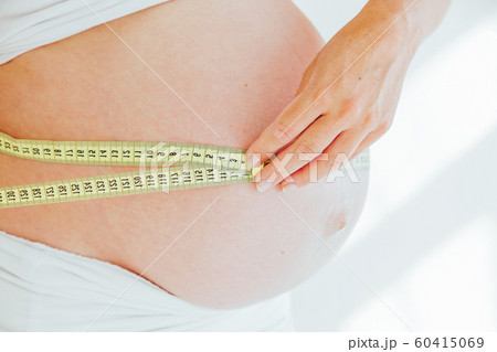 the stomach of a pregnant woman and a measuring tape the stomach of a pregnant woman and a measuring tape 60415069