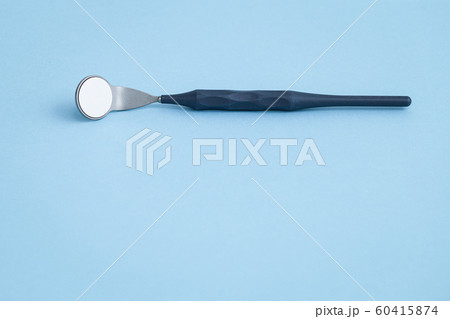 Dental mirror laying on light blue background 60415874