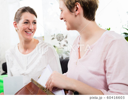 Two happy woman sitting together Two happy woman sitting together 60416603
