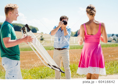 Photographer, model, and assistant on set during a photo shoot 60416642